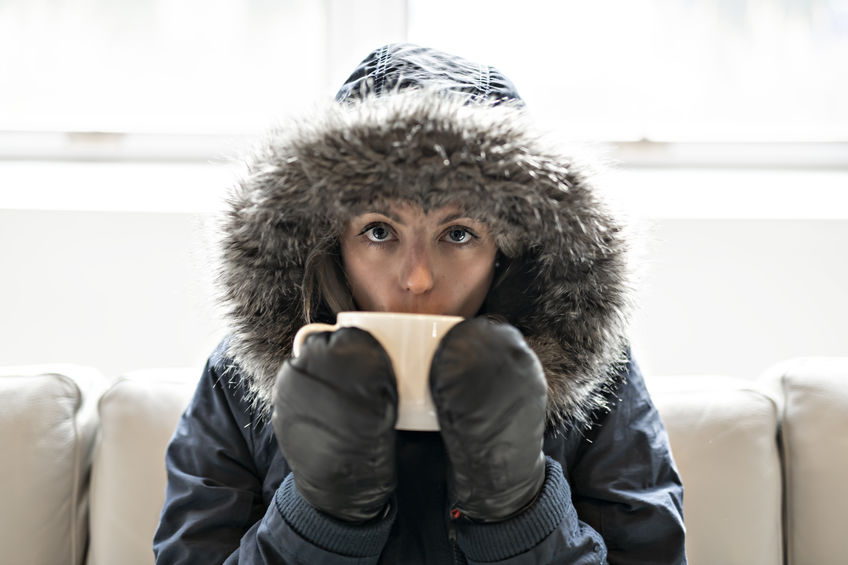 Woman in winter coat with hot drink at home