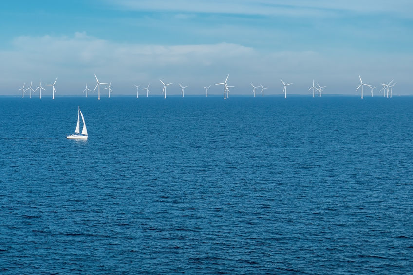 Sailboat and wind turbines on open sea